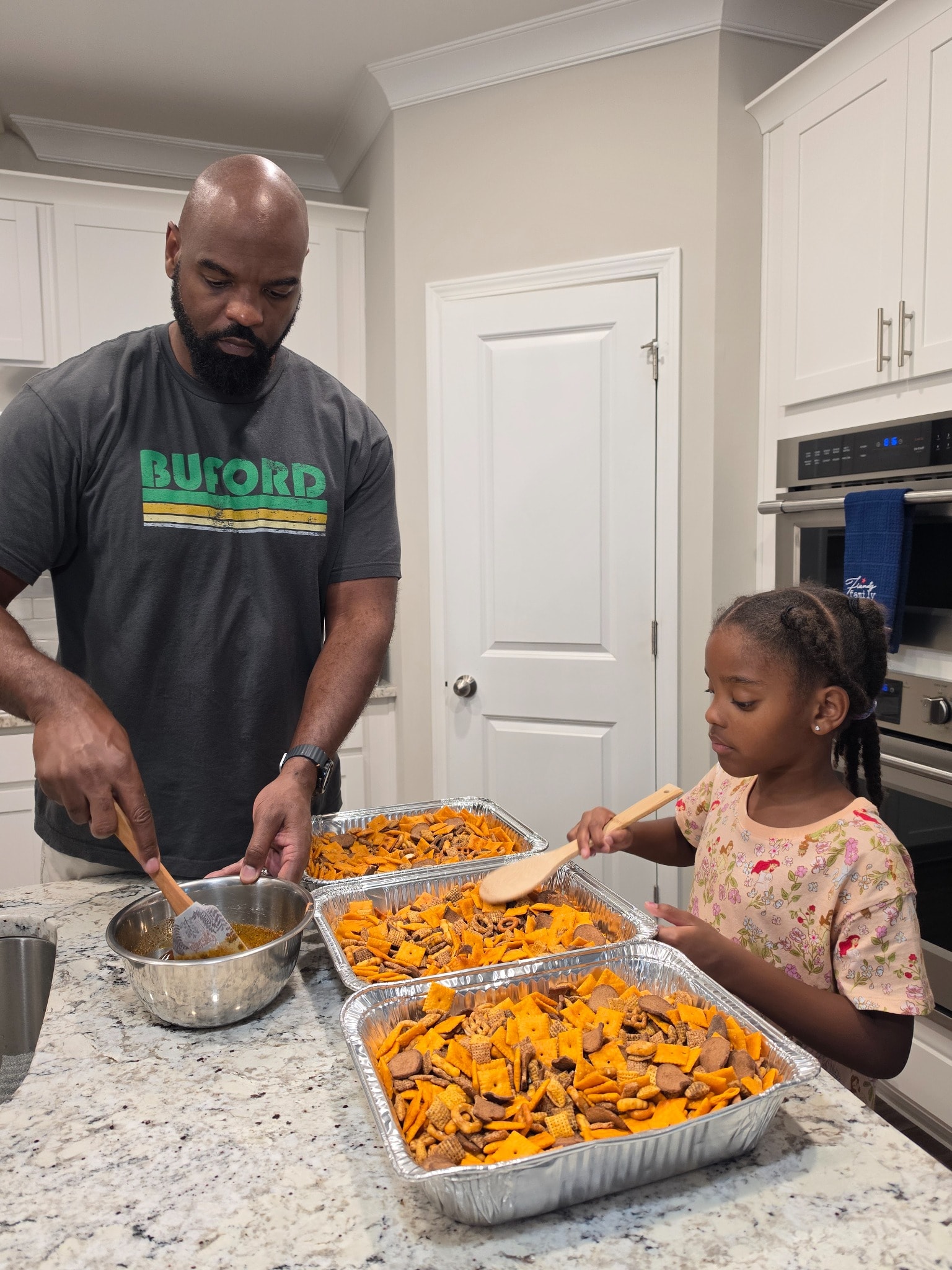 Dad and Luna preparing Luna & Dad Smokehouse snack mix together at the kitchen island in Buford, Georgia